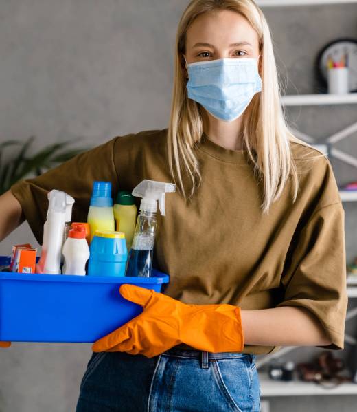 Blonde european woman in face mask posing with cleaning product at home